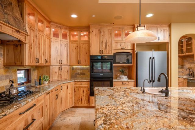 a kitchen with stainless steel appliances kitchen island granite countertop a refrigerator a stove and a sink with granite countertops