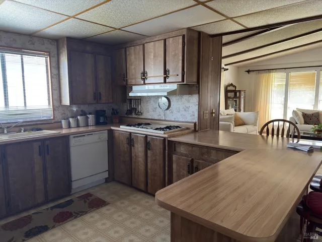 a kitchen with stainless steel appliances granite countertop a stove a sink dishwasher and microwave with wooden cabinets