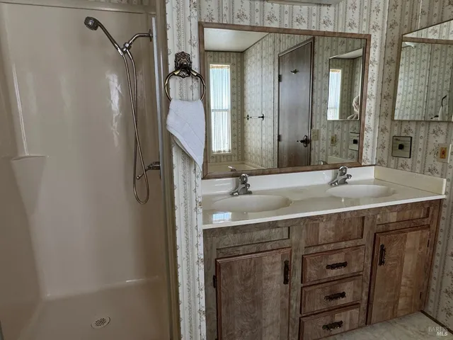 a bathroom with a granite countertop sink a mirror and a shower