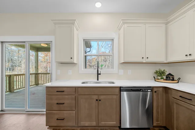 a kitchen with white cabinets and window