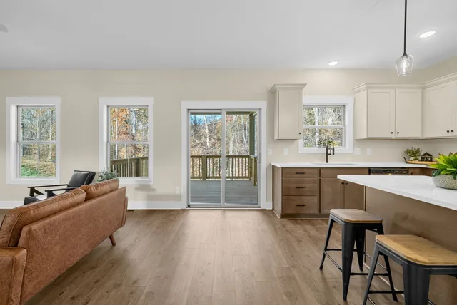 a large living room with stainless steel appliances granite countertop a couch a stove a dining table and chairs with wooden floor