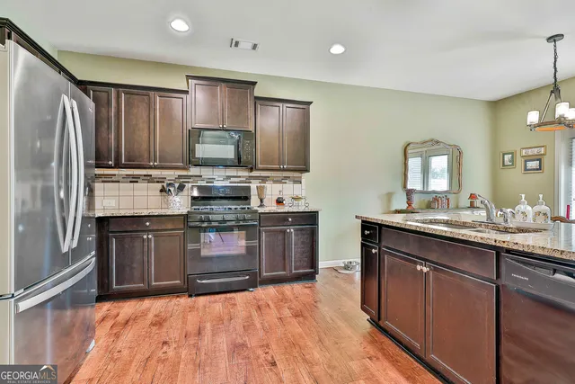 a kitchen with stainless steel appliances granite countertop a stove refrigerator and a sink
