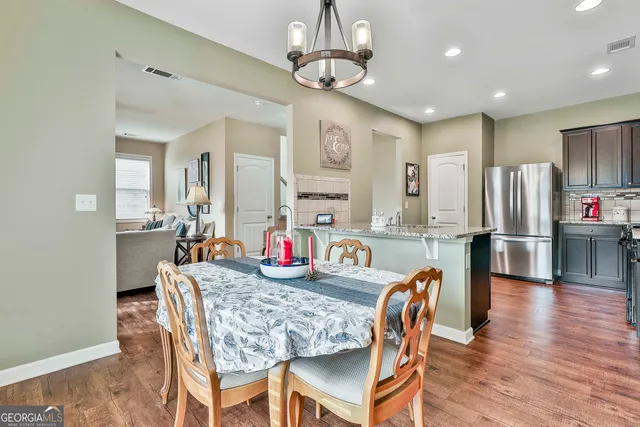 a kitchen with stainless steel appliances granite countertop a dining table chairs refrigerator and microwave