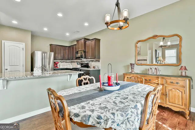 a kitchen with stainless steel appliances granite countertop a dining table chairs sink and cabinets