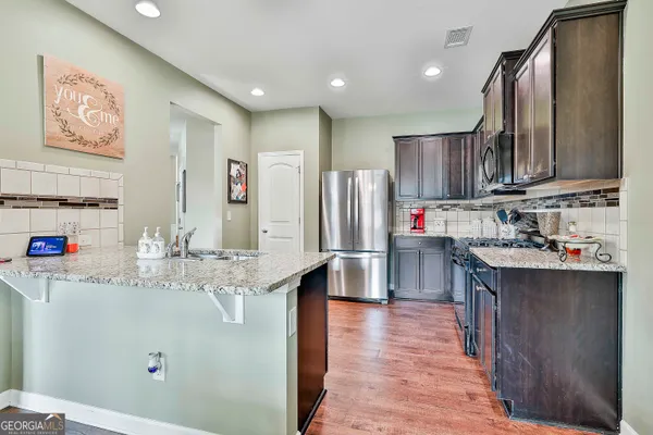 a kitchen with stainless steel appliances granite countertop a refrigerator sink and wooden cabinets
