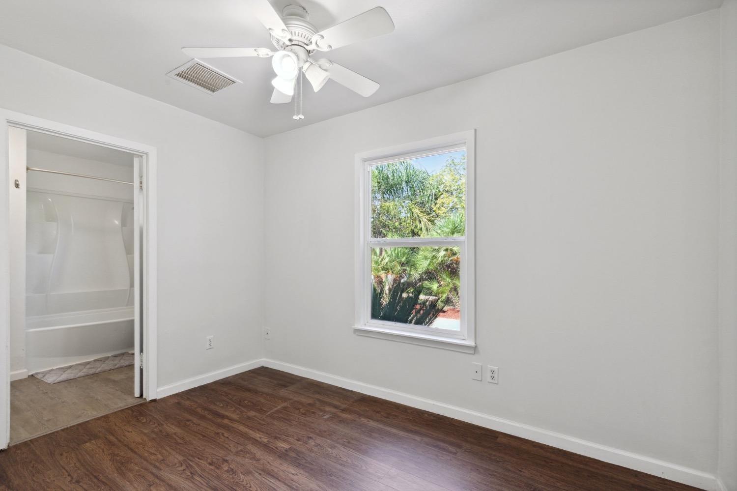 220 Sunnyside Avenue Clovis, CA 93612 - Photo 14 of 38 an empty room with wooden floor chandelier fan and windows