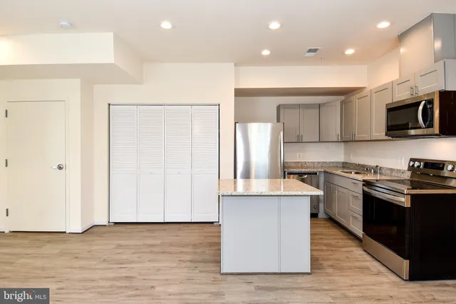 a kitchen with stainless steel appliances granite countertop a stove top oven a sink and a refrigerator