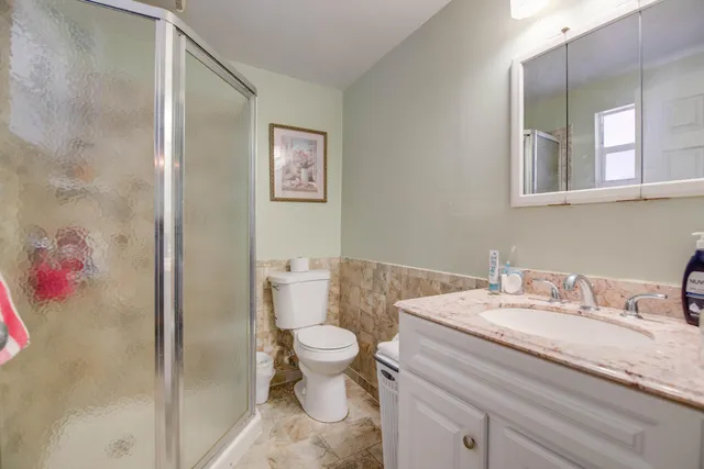 a bathroom with a granite countertop sink mirror vanity and toilet