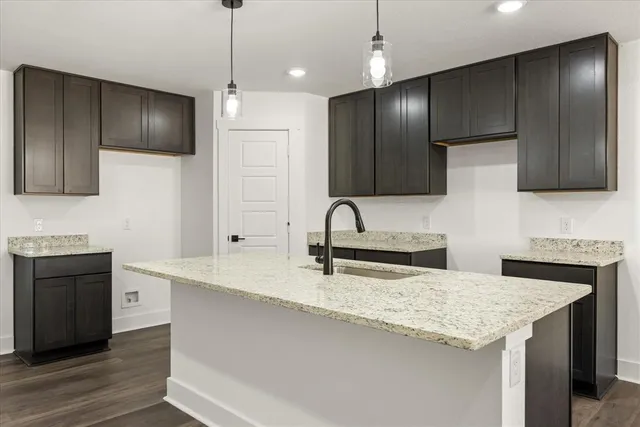 a kitchen with stainless steel appliances granite countertop a sink a stove a refrigerator cabinets and wooden floor