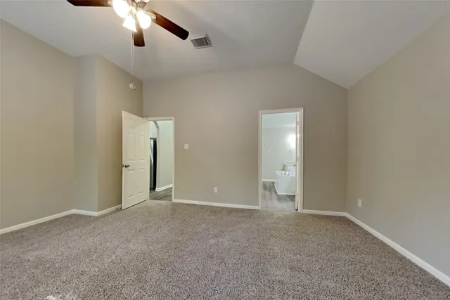 an empty room with chandelier fan and windows
