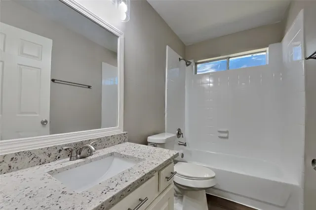 a bathroom with a granite countertop sink a toilet a mirror and shower