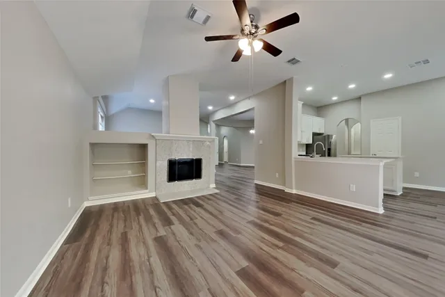 a view of a kitchen and an empty room with wooden floor