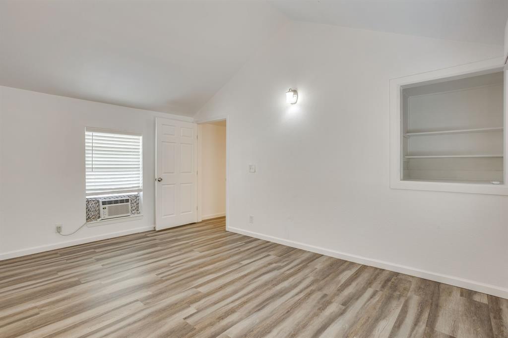 6940 Hatch Road Fort Worth, TX 76135 - Photo 36 of 40 Vaulted ceiling with a wall-mounted light fixture, wood-finish flooring, built-in shelving, and a window with blinds