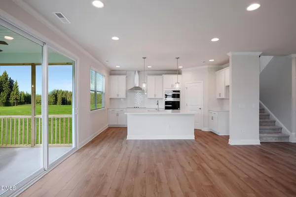 a view of kitchen with kitchen island wooden floor refrigerator and stove