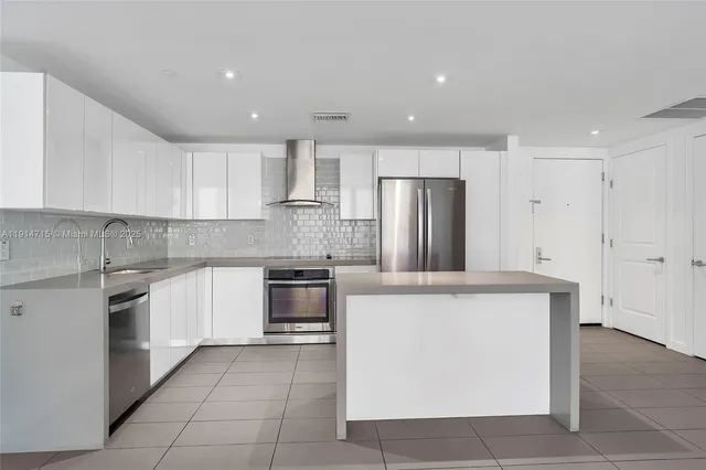 a kitchen with stainless steel appliances granite countertop a stove top oven a sink and a refrigerator