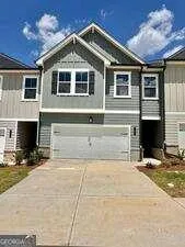 a front view of a house with yard and parking