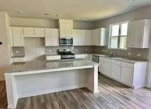 a kitchen with granite countertop white cabinets sink and window