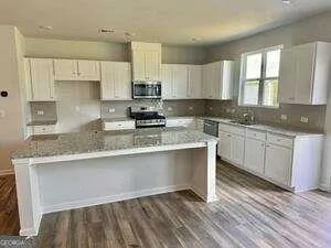 a kitchen with stainless steel appliances granite countertop a sink a stove a window and white cabinets