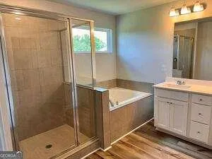 a spacious bathroom with a granite countertop sink a mirror and shower