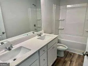 a bathroom with a sink toilet double vanity and shower
