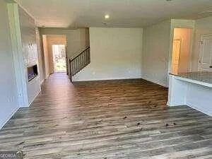 a view of a livingroom with wooden floor and staircase