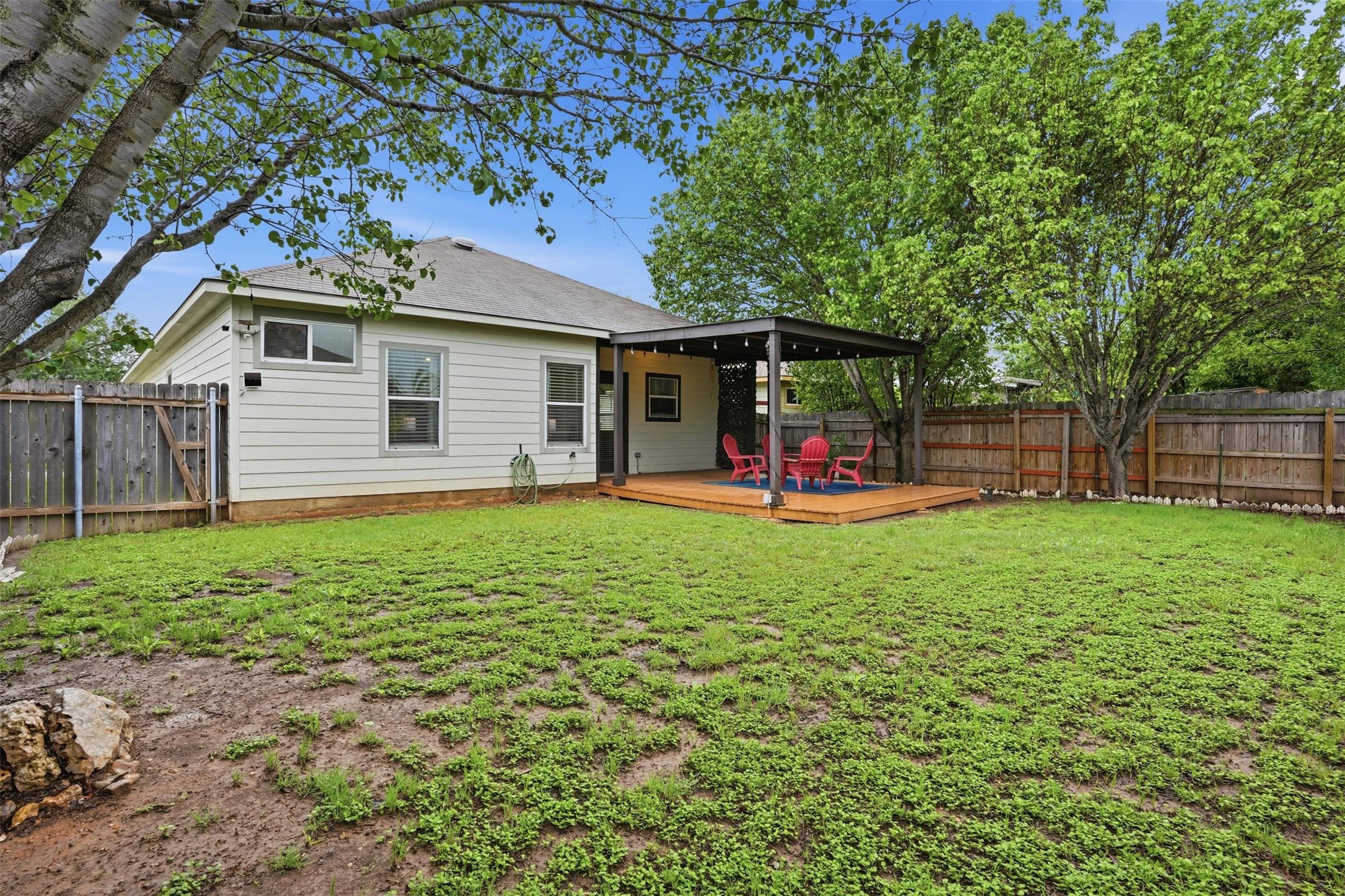 11606 Murchison Street Manor, TX 78653 - Photo 29 of 35 Expansive backyard featuring a lush lawn, mature trees, and a wooden deck with a covered pergola