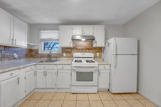 a kitchen with white cabinets a sink and white appliances