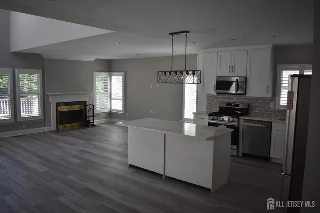 a kitchen with kitchen island granite countertop stainless steel appliances cabinets a sink and a wooden floor