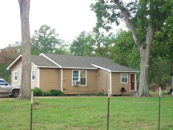 a view of a yard in front of a house with large windows