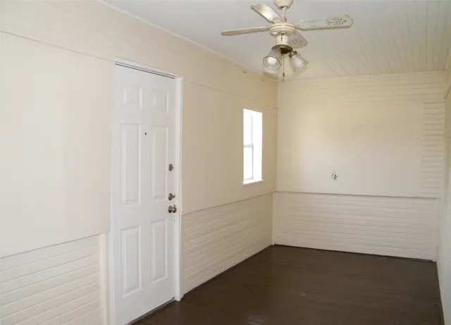 an empty room with windows and fan