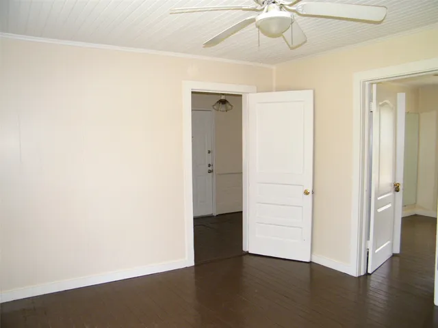 an empty room with wooden floor closet and windows