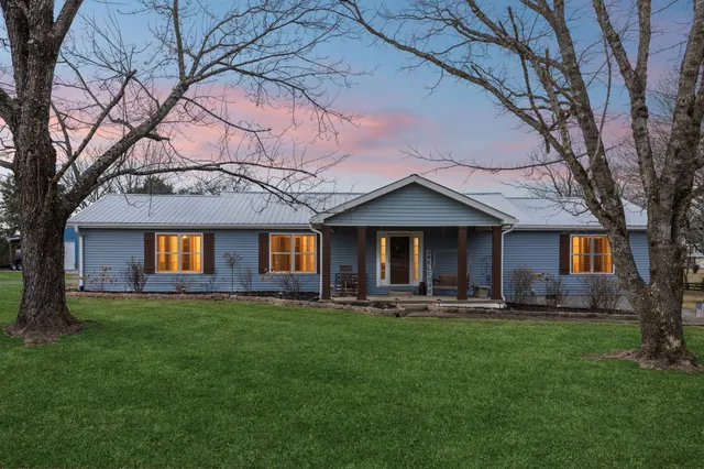 a front view of a house with a yard and trees