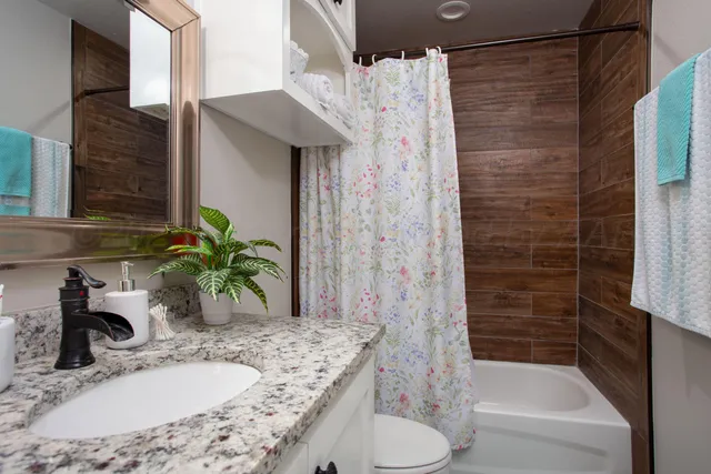 a bathroom with a granite countertop sink and a bathtub