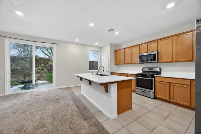a kitchen with stainless steel appliances granite countertop a stove top oven a sink dishwasher a refrigerator and a microwave oven with wooden cabinets