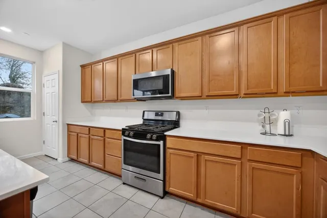 a kitchen with stainless steel appliances granite countertop a stove a sink dishwasher and a microwave oven with cabinets