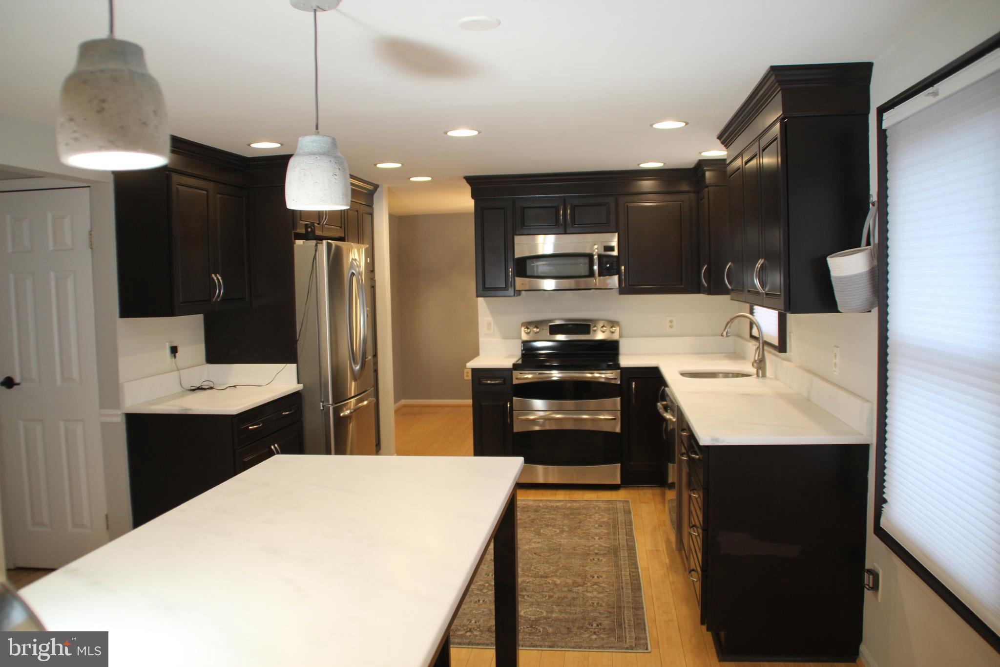 12507 Thunder Chase Drive Reston, VA 20191 - Photo 6 of 27 a kitchen with kitchen island a sink stainless steel appliances and cabinets