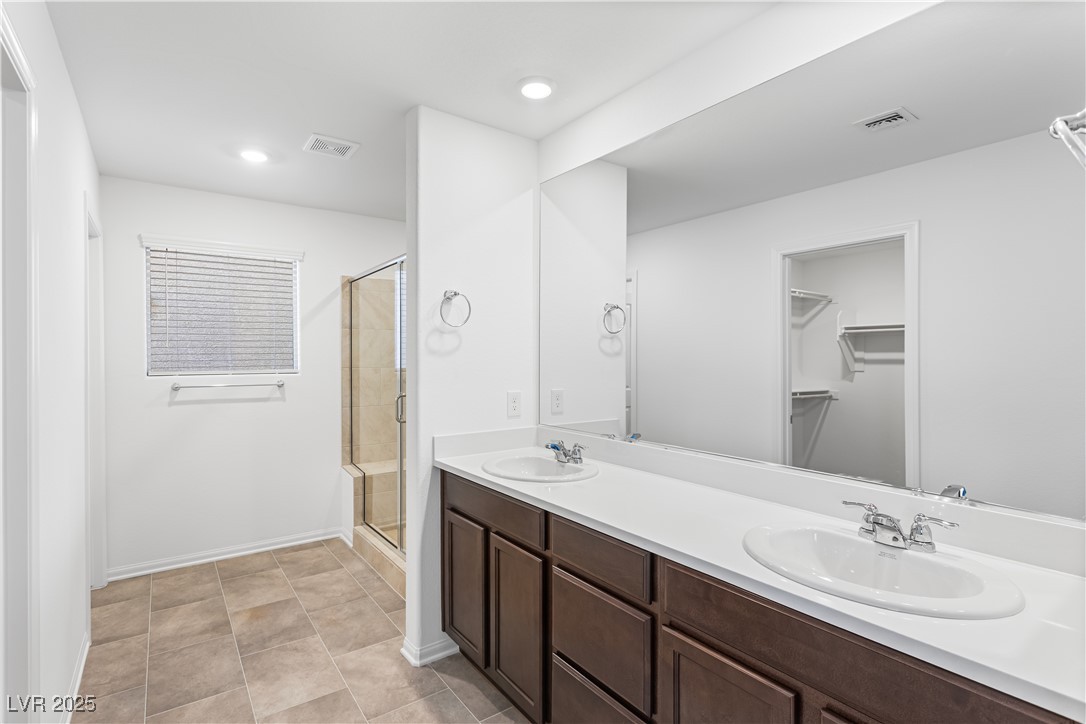 5646 Spring Trellis Street Las Vegas, NV 89113 - Photo 6 of 25 Full bathroom featuring a shower stall, double vanity, a walk in closet, recessed lighting, and light tile patterned floors