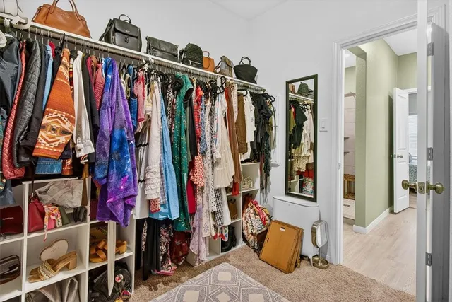a view of walk in closet with clothes and shoes