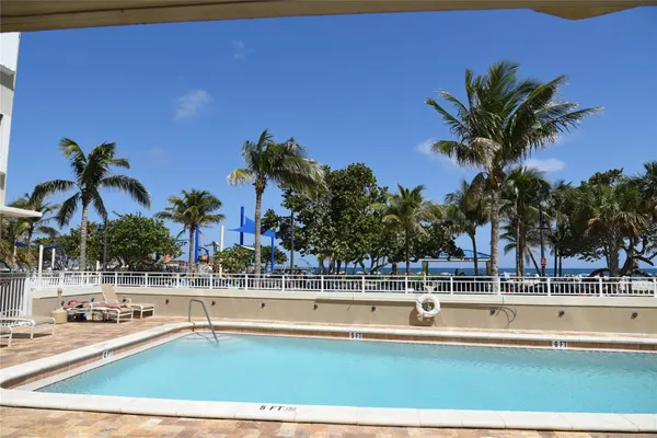 a view of swimming pool with outdoor seating and house in the background