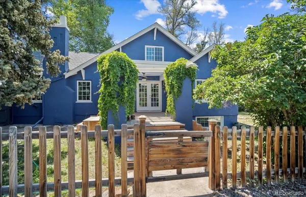 a view of a house with wooden fence next to a yard