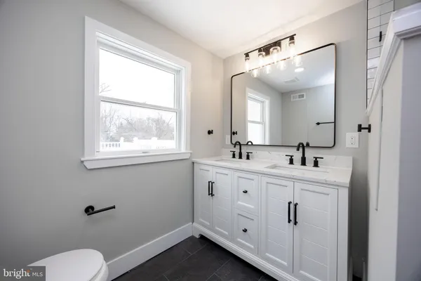 a bathroom with 2 sink toilet and a mirror