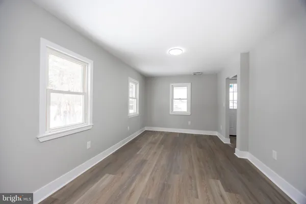 a view of an empty room with wooden floor and window