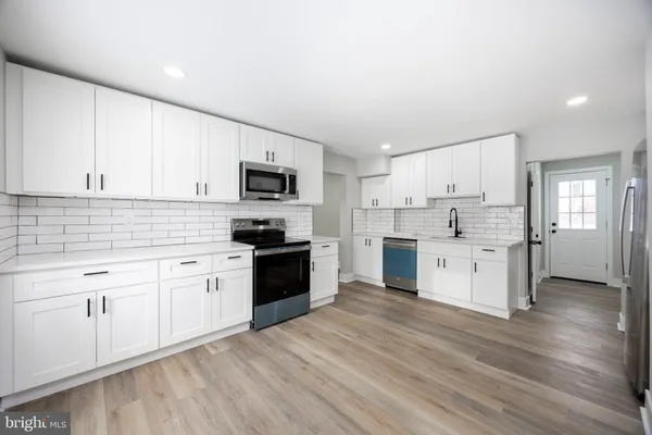 a kitchen with granite countertop white cabinets and stainless steel appliances