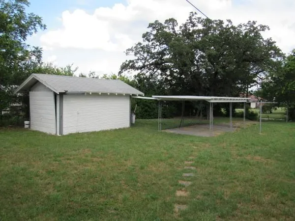 a backyard of a house with plants and large trees