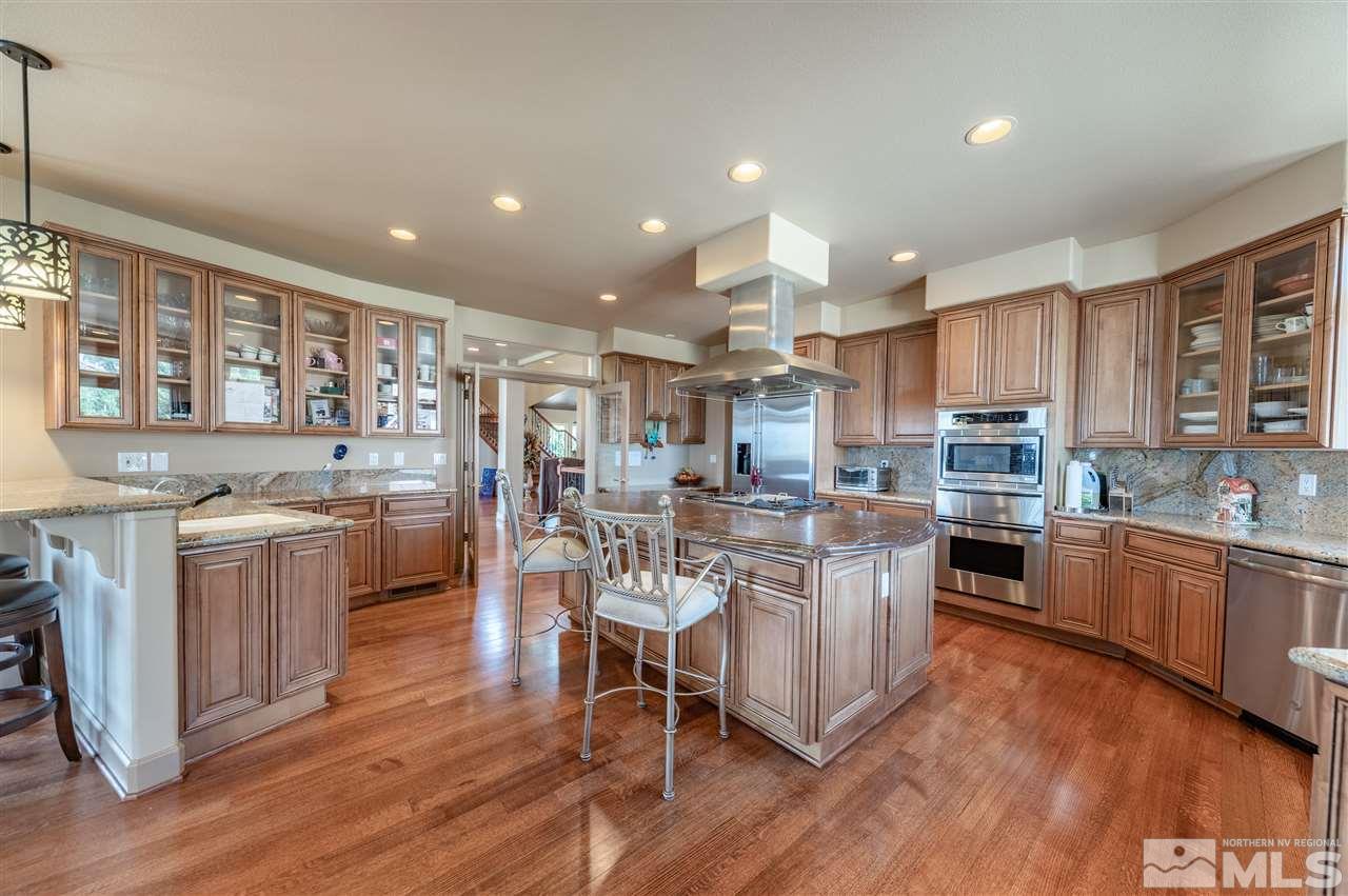 10055 Trailside Court Reno, NV 89511 - Photo 13 of 26 a kitchen with stainless steel appliances kitchen island granite countertop wooden floors and white cabinets