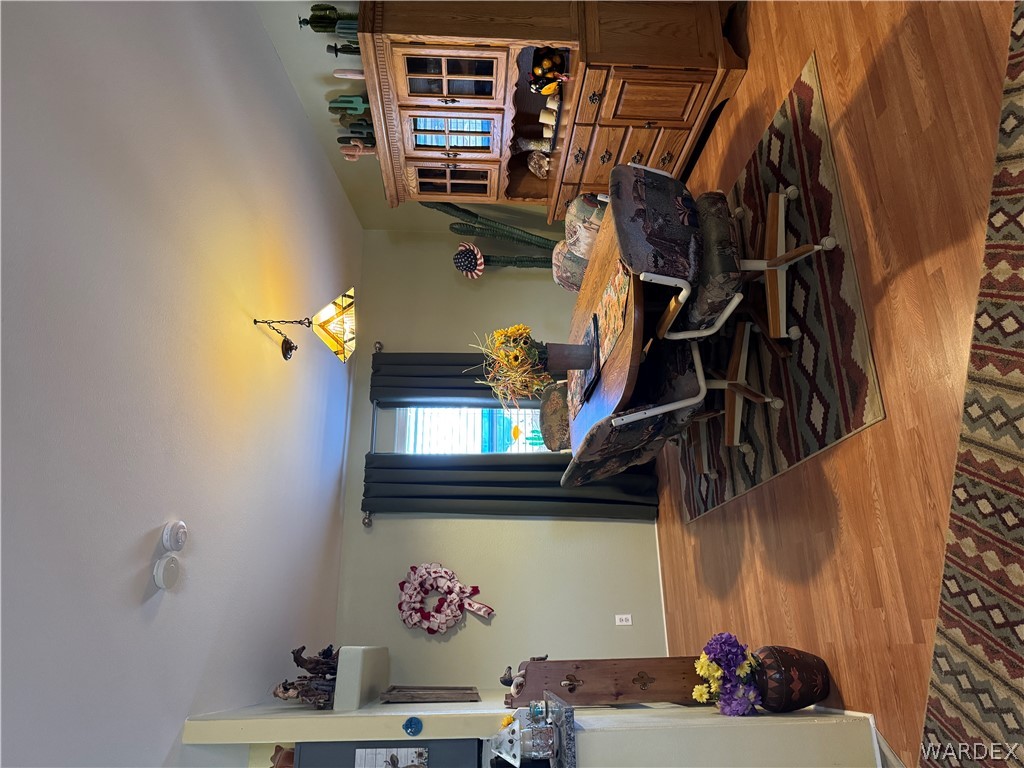 4222 Estrella Road Golden Valley, AZ 86413 - Photo 14 of 34 Dining area featuring light wood flooring, a window with dark curtains, and a wooden hutch with glass-fronted cabinets
