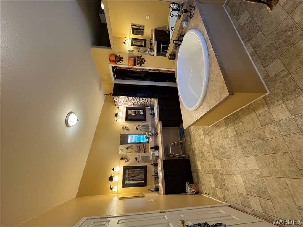4222 Estrella Road Golden Valley, AZ 86413 - Photo 17 of 34 Spacious bathroom featuring a large built-in bathtub, dual vanities with dark cabinetry, and tile flooring