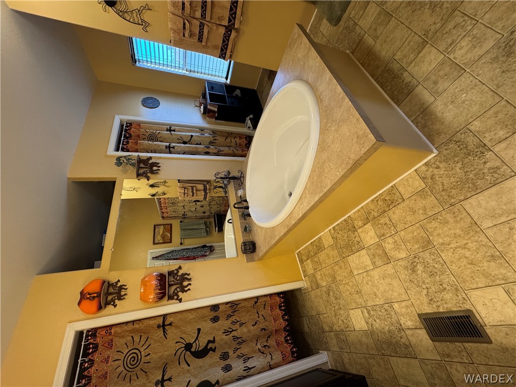 4222 Estrella Road Golden Valley, AZ 86413 - Photo 19 of 34 The bathroom features a built-in oval soaking tub with a surrounding countertop, tiled flooring, and a large mirror above the vanity area