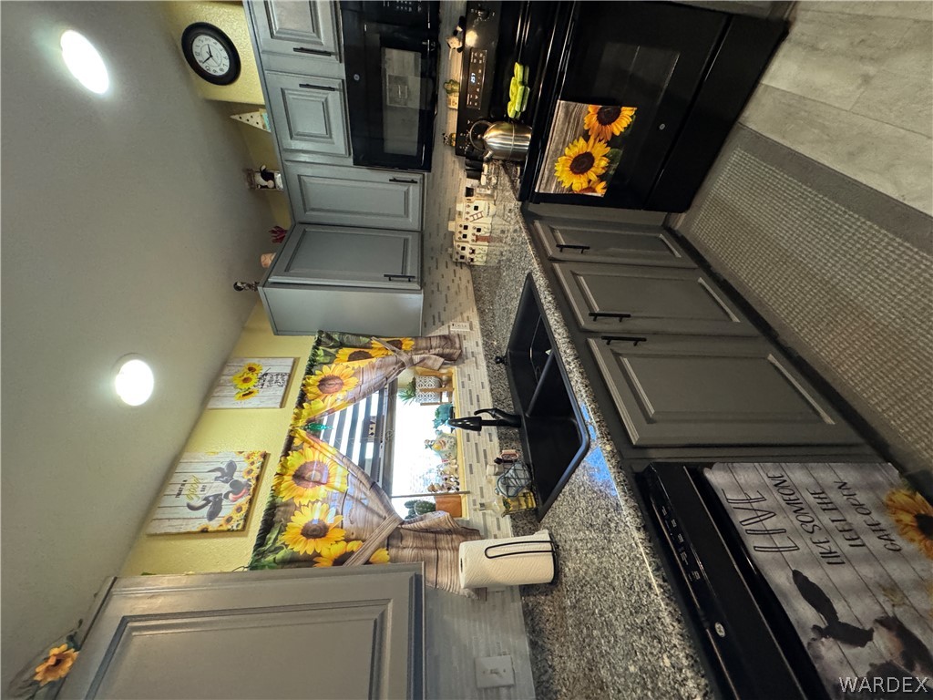 4222 Estrella Road Golden Valley, AZ 86413 - Photo 23 of 34 The kitchen features gray cabinetry with dark hardware, granite countertops, a black sink with a matching faucet, and a black range