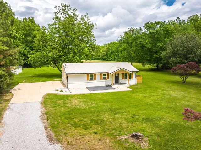 a white house with a big yard and large trees